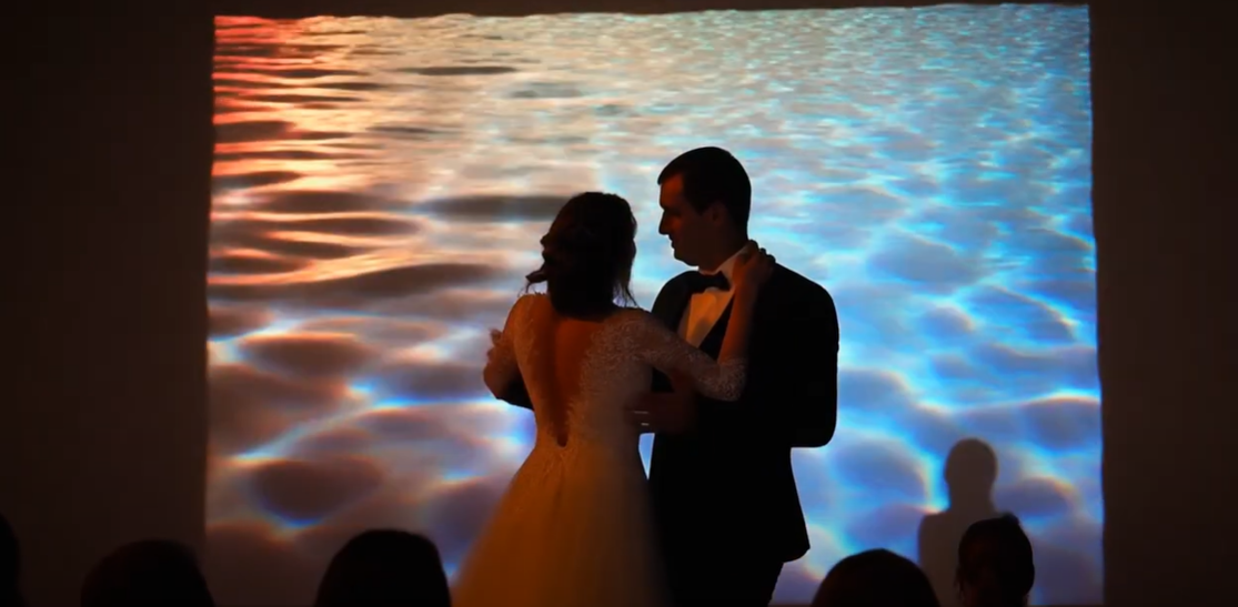 Bride and groom dancing in front of video projection